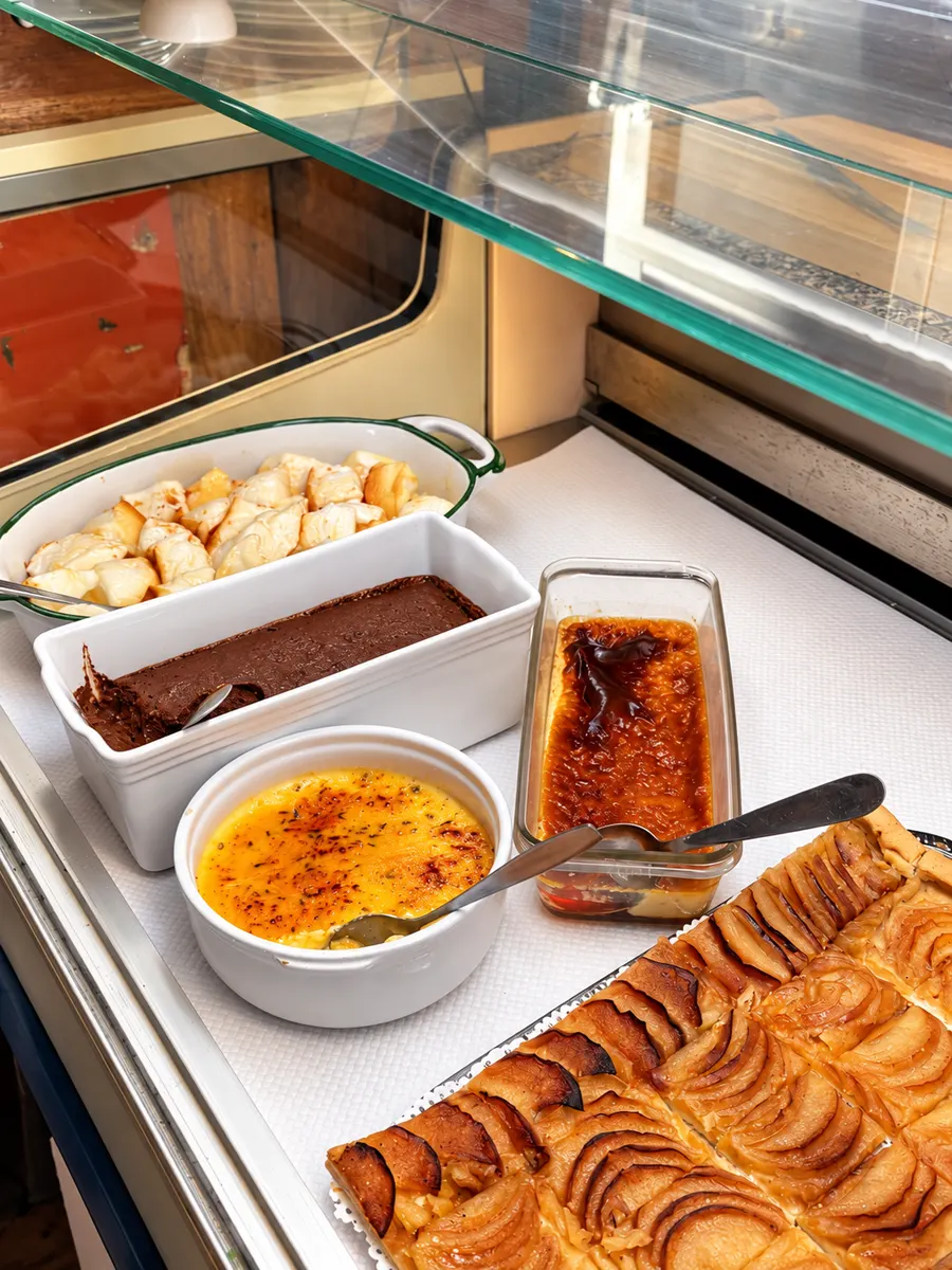 Desserts in der Vitrine: Crème brûlée, Mousse au chocolat, Crème caramel und Apfeltarte.
